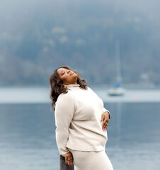 African female adult posing by lake on cloudy day