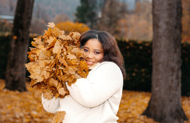 African female smiling with autumn leaves in park © Ktn