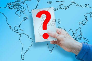 DOUBTS AND UNCERTAINTIES ABOUT GLOBAL TRENDS - Concept with global map and hand holding a question mark