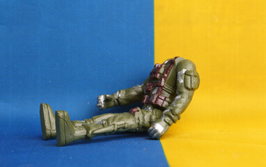 figurine of a headless soldier against the background of the Ukrainian flag.Concepts of war in...