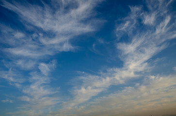 Whimsical clouds dance across a brilliant blue sky at sunset