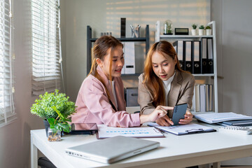 Obraz premium Businesswoman sitting at desk on couch in workplace or at home working on laptop and analyzing data on charts and graphs and writing on papers to make business plan and strategies for company.