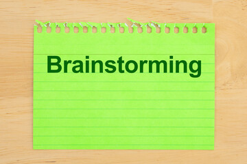 Green notepad with the word brainstorming written on it