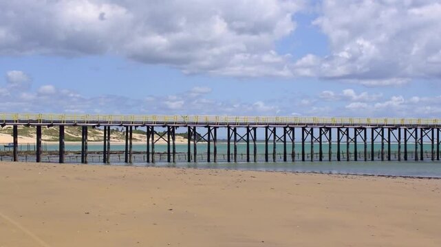 Bridge in Paracuru beach in Ceara, Brazil. With sea and dunes in the background.