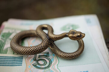 A statuette of a metal snake and paper money.