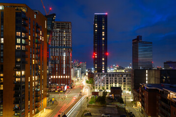 Elevated view of high rise residential buildings and shops along a busy street in Manchester at night