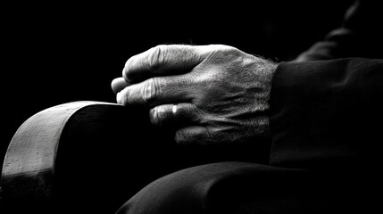 Obraz premium Close-up black and white photo of elderly person's hands clasped together on lap.