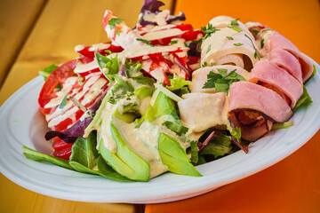 chef salad topped with ham, turkey, and avocado