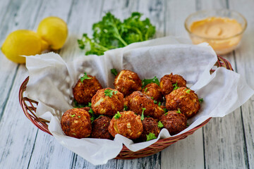 basket of crispy fried crab meatball fritters served with fresh parsley and lemon