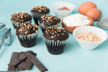 top view and detail Chocolate muffin or cupcake with egg and cake ingredients on blue background. Home baking concept