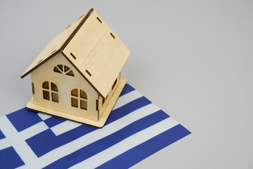 Real estate in Greece concept. Wooden house model on Greek flag. Copy space for text.	