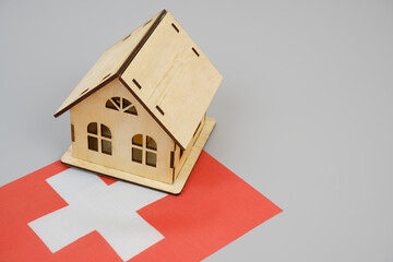 Wooden house model and Swiss flag on gray background. Copy space for text.