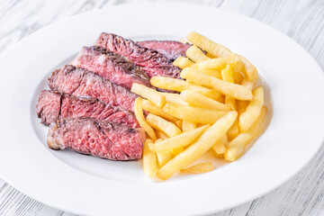 Sliced Medium-Rare Ribeye Steak with French Fries on White Plate
