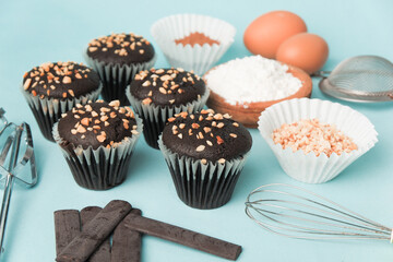 top view and detail Chocolate muffin or cupcake with egg and cake ingredients on blue background. Home baking concept