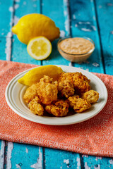 crispy fried oysters with fresh lemon and a remoulade dipping sauce, on blue tabletop