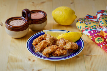 crispy fried oysters with fresh lemon and a remoulade dipping sauce, on wooden tabletop