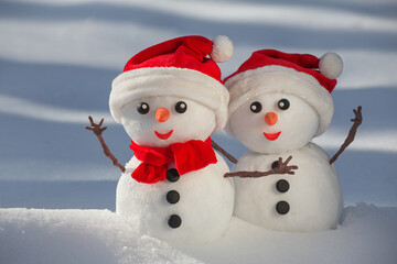 View of a couple of snowmen in a santa hats on their heads in a winter forest. Holiday christmas...