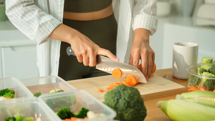 Close up of young woman preparing nutritious meal containers for the week in a kitchen. Healthy lifestyle and nutrition concept.
