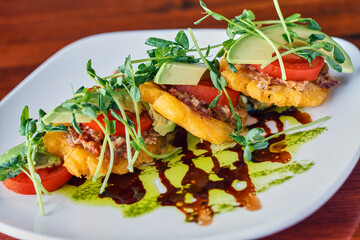 a salad consisting of sliced roma tomatoes and fried green tomatoes
