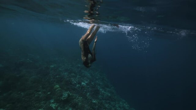 Woman freediver in costume swims in tropical sea on coral reef. Girl freediving in ocean, underwater view. Concept of active sport, lifestyle. Pretty girl diver. Crystal blue water, sun rays shining