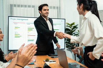 Cheerful meeting room, businesspeople celebrate with handshaking. Successful project was completed before the deadline. Business partnership and collaboration in project management. Habiliment