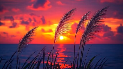 Silhouetted Grass Blades at Vibrant Sunset Over Water