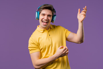 Positive man listening music, playing on air guitar, enjoying with headphones