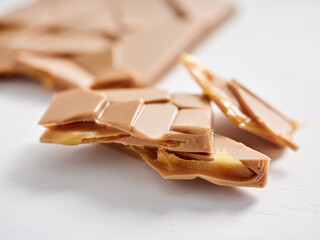 Various caramel chocolate pieces display their smooth texture and rich color on a clean white surface. Perfect for snacking or dessert, they invite indulgence and enjoyment
