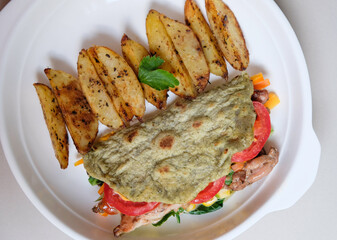 Baked potato wedges and tortilla wrap with roasted chicken and vegeteble served in a plate.