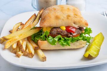 hamburger  with lettuce and tomatoes served on a ciabatta roll