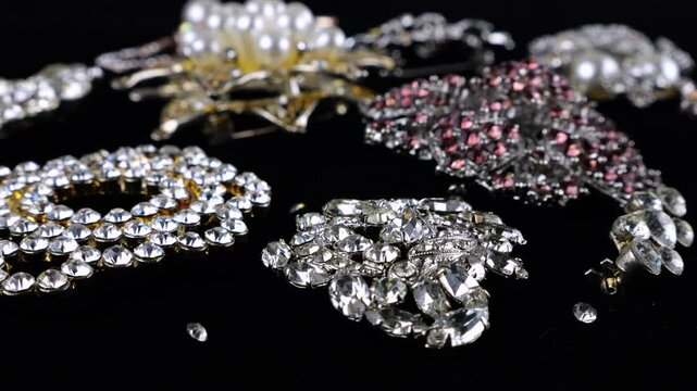 Vintage costume jewelry, brooches with crystals and artificial pearls on a rotating black velvet display case.