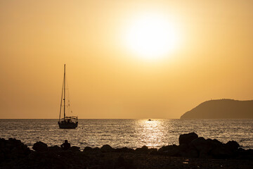 A mesmerizing orange sunset in Bar, Montenegro, with the sun peeking through clouds and the...