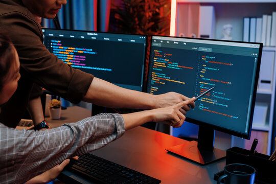 IT developers discussing with point to intelligent website development coder system running data online two screens information technology at neon light room at modern office. Infobahn.