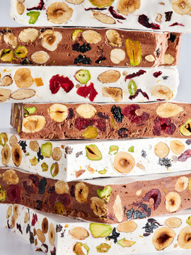 Different layers of nougat stacked together highlight a variety of nuts and dried fruit. The colorful textures and contrasts create an appealing visual. Perfect for festive occasions