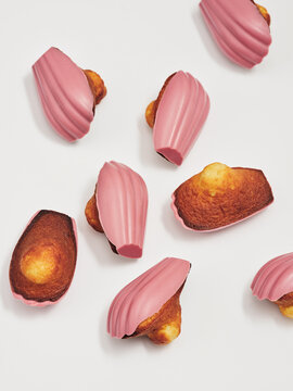 Baked goods with vibrant pink coating are arranged artistically on a smooth surface, highlighting their unique shapes and textures. These treats are perfect for gatherings