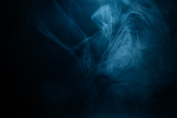 Wispy blue smoke spreads across a dark surface, creating a surreal and atmospheric effect. The intricate swirls add a dreamy and mysterious aesthetic.