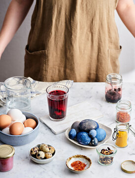 A glass with a staining solution and an egg in it and already stained blue eggs