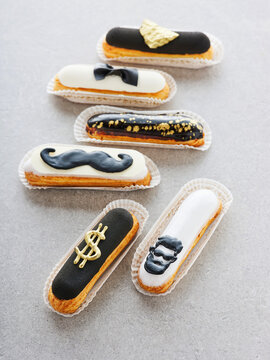 An array of unique pastries resembling stylish characters are arranged on a light gray surface. These delightful treats showcase various designs, perfect for a celebratory event