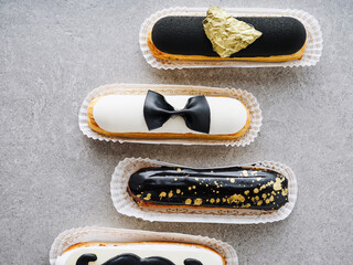 Decorative pastries are arranged in a stylish manner, showcasing a variety of black and white designs, including bow ties and shimmering gold details. Perfect for an upscale event or celebration