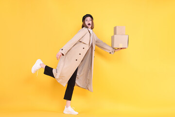 Emotional postwoman with parcels on yellow background