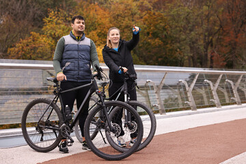 Obraz premium Beautiful happy couple with bicycles spending time together outdoors, space for text