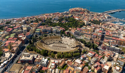 Aerial view of the Flavian Amphitheater, located in the historic center of Pozzuoli, near Naples, Italy. In the background are the Tyrrhenian Sea and the promontory of Capo Miseno.