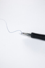 Black biros on white background with painted line on paper. Concept: Education, stationery, study, commerce.