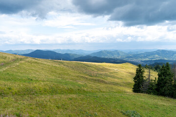 Fototapeta premium Mountains ranges in the Carpathians. Hills, forest and meadows. Green valley. Cloud sky landscape