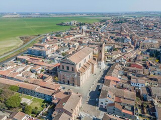 Aerial view of the Duomo di Comacchio, the Basilica Concattedrale di San Cassiano Martire, surrounded by the historic old town with its traditional red-roofed buildings.