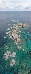 Aerial view of Punta Falcone in Sardinia near Santa Teresa. The jagged rocks rise out of the turquoise-coloured water, surrounded by the endless sea and dramatic sky.