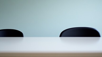 Two Black Chairs at a White Table Against a Pale Green Wall