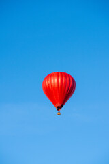 Flying red hot air balloon in the blue sky