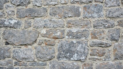 Obraz premium Rustic gray stone wall with irregularly shaped rocks and mortar for a timeless earthy texture
