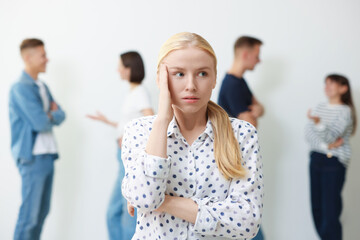 Young woman feeling uncomfortable among people indoors, selective focus